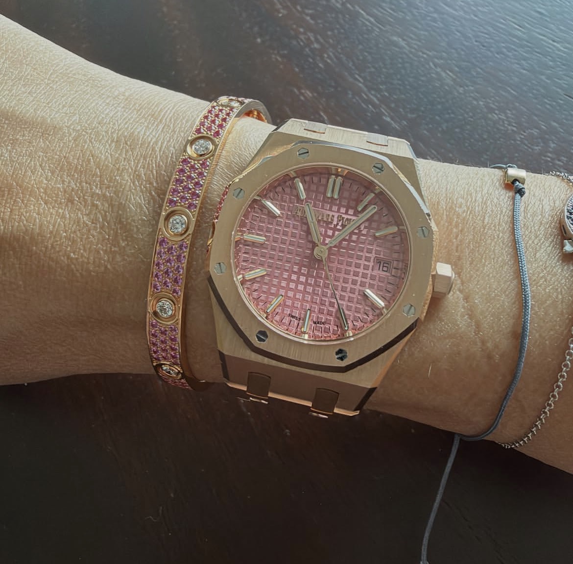 Audemars Piguet Royal Oak in pink gold with a pink Grande Tapisserie dial, worn beside a Cartier Love bracelet set with pink sapphires