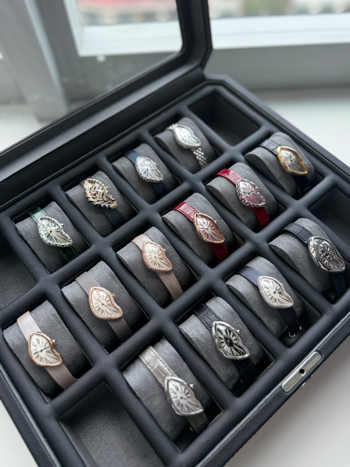 Close-up of Cartier Crash watches in a grey watch case, including gem-set, pink gold and white gold models