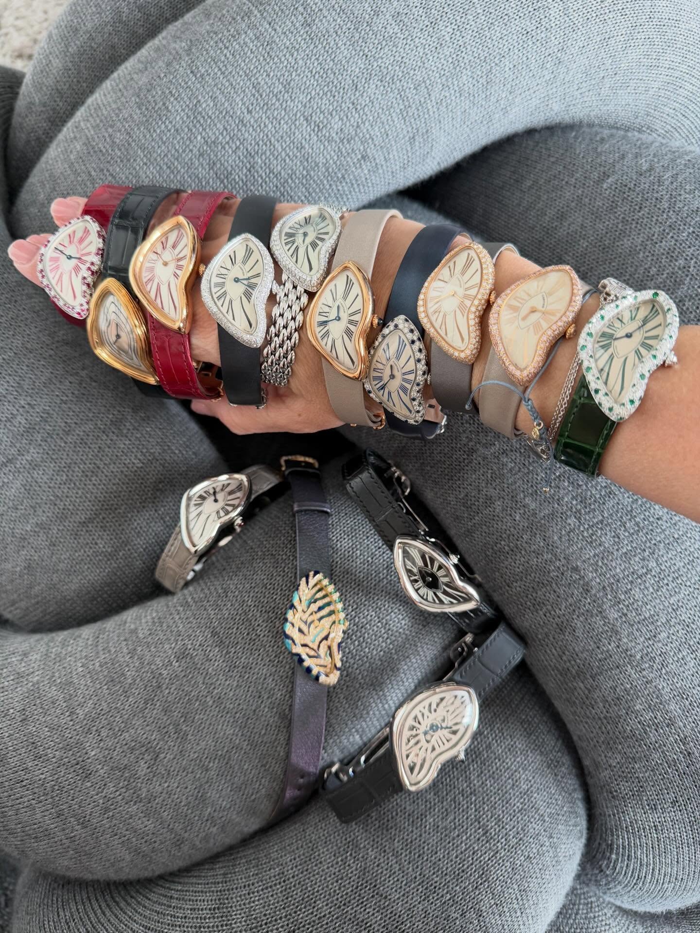 Eleven Cartier Crash watches stacked along one arm, with three more laid out below